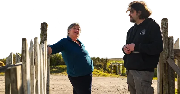 Una vecina conversa con el equipo junto a una reja de madera